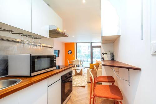une cuisine avec un évier et un comptoir avec des chaises dans l'établissement Appartement Coloré aux portes des Buttes Chaumont, à Paris