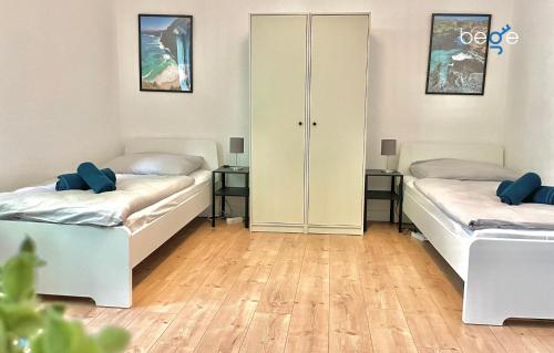 twee bedden in een kamer met twee tafels bij BEGE APARTMENTS WorkStay Lodge in Essen
