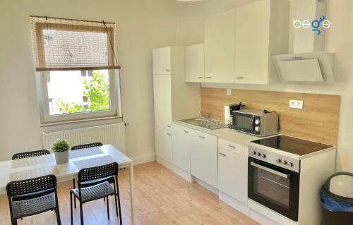 een keuken met witte kasten en een tafel met stoelen bij BEGE APARTMENTS WorkStay Lodge in Essen