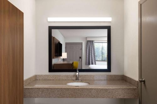 a bathroom with a sink and a mirror at Day's Inn & Suites by Wyndham Indianapolis Airport East in Indianapolis