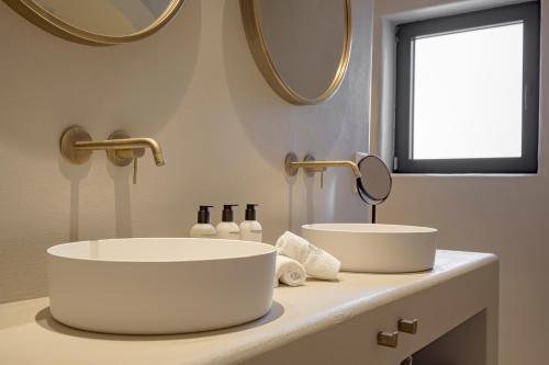 a bathroom with two sinks and two mirrors at Boutique Hotel Los Limoneros in Moraira