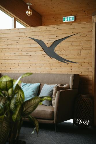 a couch against a wooden wall with a clock on it at Hotel Vík í Mýrdal in Vík