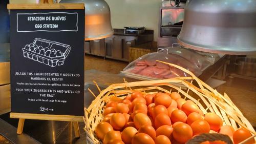 un panier de tomates sur une table avec une pancarte dans l'établissement Ohtels La Hacienda, à La Pineda