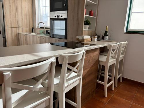 une cuisine avec un comptoir et des tabourets blancs dans l'établissement Apartamento LAS FLORES, à Puerto de la Cruz