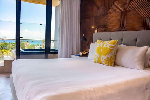 a bedroom with a large white bed with a large window at The Fives Downtown Hotel & Residences, Curio Collection by Hilton in Playa del Carmen