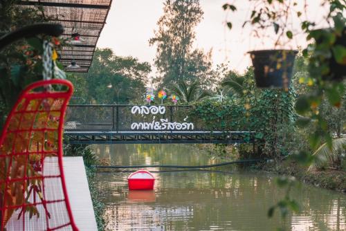 a red boat in the water under a bridge at Klong Cafe & Resort in Pathum Thani