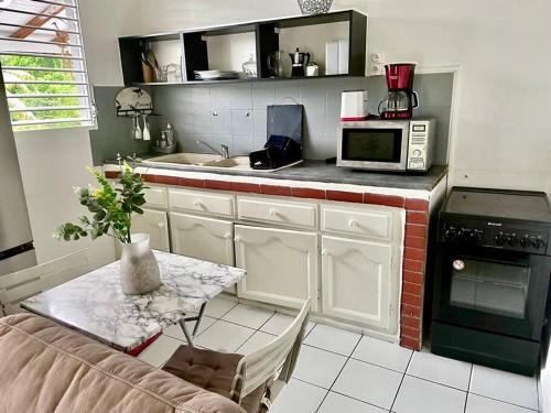 a kitchen with a table and a microwave at Johanny Home in Les Abymes
