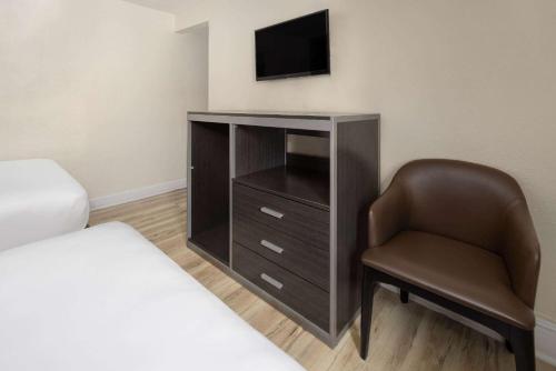a bedroom with a bed and a chair and a television at Wildwood Inn Hotel Travelodge Beach & Boardwalk in Wildwood