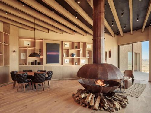a fireplace in a living room with a table and chairs at Banyan Tree Veya, Valle de Guadalupe - A Wellbeing & Wine Resort in Valle de Guadalupe