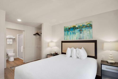 a bedroom with a white bed and a bathroom at WaterWalk Extended Stay by Wyndham Charlotte - Arrowood in Charlotte