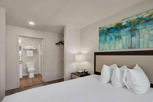 a bedroom with a white bed and a bathroom at WaterWalk Extended Stay by Wyndham Charlotte - Arrowood in Charlotte