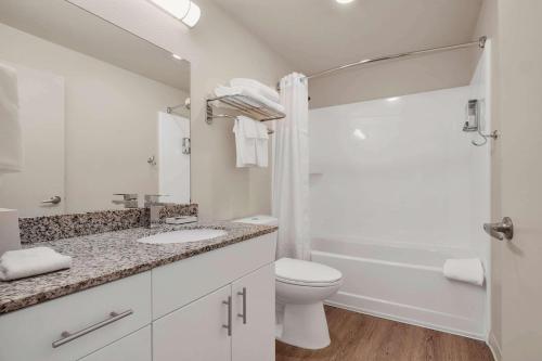 a white bathroom with a toilet and a sink at WaterWalk Extended Stay by Wyndham Charlotte - Arrowood in Charlotte