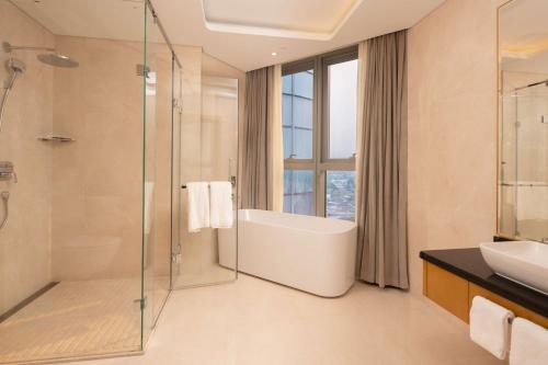 a bathroom with a shower and a tub and a sink at Hilton Brazzaville Les Tours Jumelles Hotel & Residences in Brazzaville