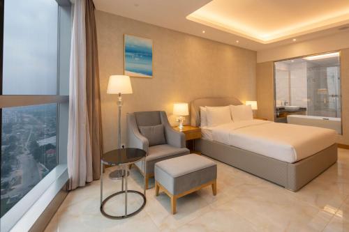 a bedroom with a bed and a chair and a window at Hilton Brazzaville Les Tours Jumelles Hotel & Residences in Brazzaville
