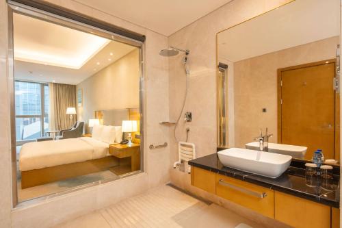 a bathroom with a bed and a sink and a shower at Hilton Brazzaville Les Tours Jumelles Hotel & Residences in Brazzaville