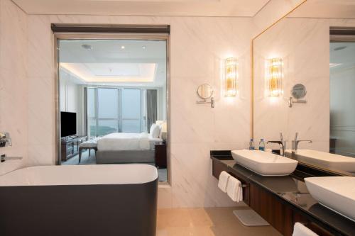a bathroom with two sinks and a large mirror at Hilton Brazzaville Les Tours Jumelles Hotel & Residences in Brazzaville