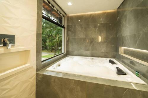 a bath tub in a bathroom with a window at Recanto Vultuoso Paraíso na Estrada Bonita com piscina aquecida Hidro Quadra de areia e Area de lazer completa in Joinville