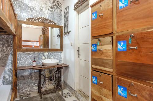 a bathroom with a sink and a wooden wall at TwoSpaces Living at Wave And Chill House, Canggu in Canggu