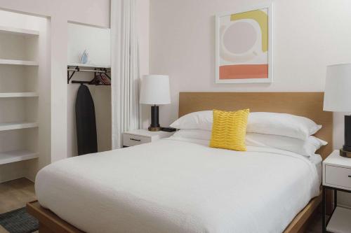 a bedroom with a white bed with a yellow pillow at WaterWalk Extended Stay by Wyndham Jacksonville Deerwood Pk in Jacksonville