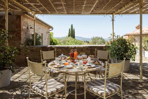 einen Tisch und Stühle unter einer Pergola in der Unterkunft Dimora Santa Margherita - Relais di Charme in Cinigiano