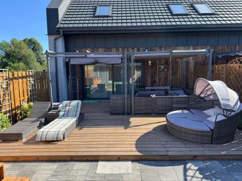 a wooden deck with a couch and chairs on it at Sielski Zaułek Guciów u Dorotki -Basen,Jacuzzi,Sauna in Guciów