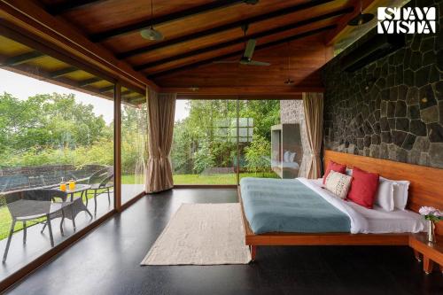 ナーシクにあるStayVista at Stonescape Villa with Pool, Lawn & Mountain Viewのベッドと大きな窓のある寝室