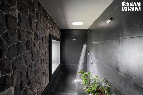 ナーシクにあるStayVista at Stonescape Villa with Pool, Lawn & Mountain Viewの石壁のバスルーム(ウォークインシャワー付)