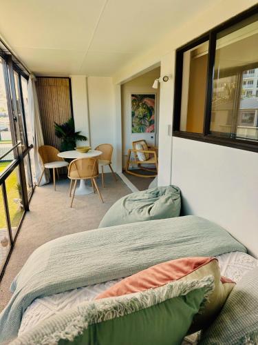 a bedroom with a bed and a table and chairs at Charm on Commons, Mauao in Mount Maunganui