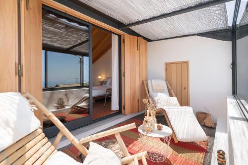 Zimmer mit einem Balkon mit Stühlen und einer Badewanne in der Unterkunft Casa da Raposeira by An Island Apart in Calheta