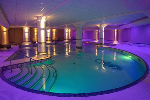 a swimming pool in a hotel with purple lighting at Dunston Hall Hotel, Spa & Golf Resort in Norwich