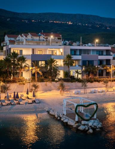 a hotel on the beach with chairs and a bed at Paoma Luxury Beach Suite with jacuzzi in Podstrana