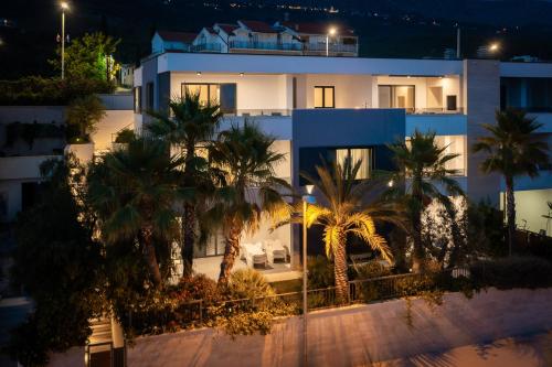 a large white building with palm trees in front of it at Paoma Luxury Beach Suite with jacuzzi in Podstrana