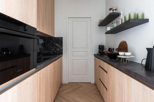 - une cuisine avec des placards en bois et des appareils noirs dans l'établissement Appartement Aulne - Welkeys, à Paris