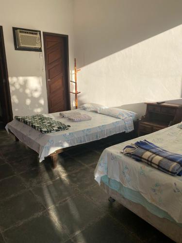 a room with two beds and a door at Pousada Recanto dos Leporage Itacuruçá in Mangaratiba