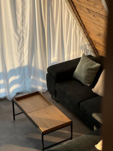 a living room with a black couch and a coffee table at Mareva House A Frame Chalet in Râmnicu Vâlcea