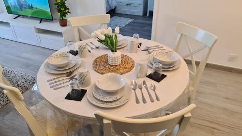 - une table à manger blanche avec des assiettes et des ustensiles dans l'établissement Chic Central, 10 Min from Paris, à Argenteuil