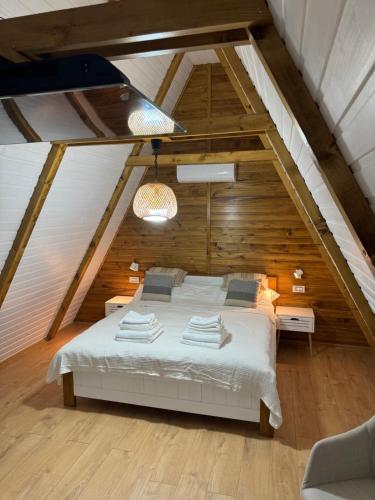 a bedroom with a white bed in a attic at Mareva House A Frame Chalet in Râmnicu Vâlcea
