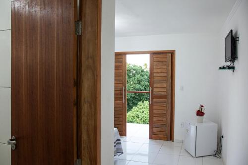 a hallway with a door and a white refrigerator at Mandacaru Flat in São Miguel do Gostoso