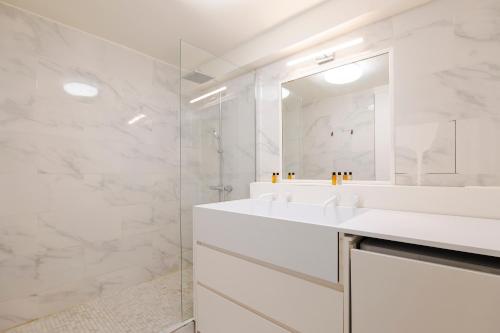 une salle de bain blanche avec deux lavabos et un miroir dans l'établissement Veeve - Chic By Bonne-Nouvelle, à Paris