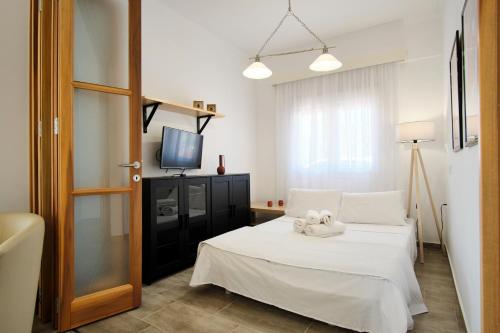 a bedroom with a white bed and a television at Villa del Capitano in Corfu Town