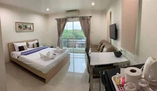 a bedroom with a bed and a couch and a window at Privacy Residence Lopburi in Lop Buri