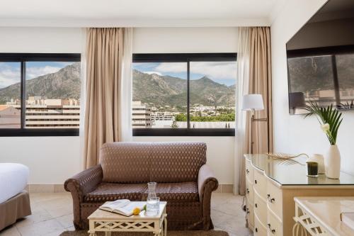 a hotel room with a chair and a bed and windows at Hotel Don Pepe Gran Meliá in Marbella