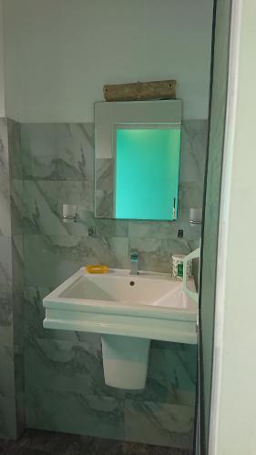 a bathroom with a white sink and a mirror at CANAAN MUSIC Hotel in Moratuwa