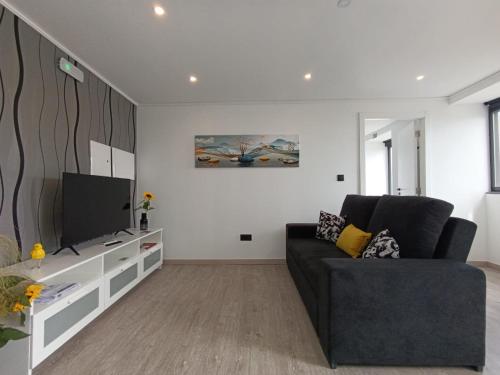 a living room with a couch and a flat screen tv at Quinta do Araçal T1 in Horta