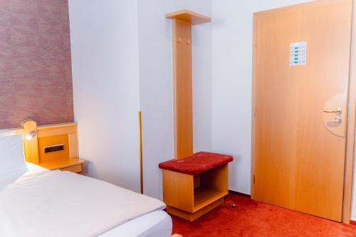 a bedroom with a bed and a red stool at Hotel Unter den Linden in Rüdesheim am Rhein