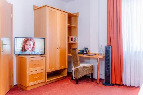a room with a desk with a tv and a table at Hotel Unter den Linden in Rüdesheim am Rhein