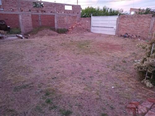 an empty yard with a brick wall and a white garage at Alojamiento Quillen in Plaza Huincul