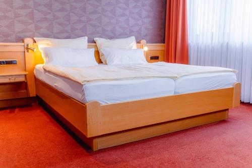 a bedroom with a bed with white sheets and pillows at Hotel Unter den Linden in Rüdesheim am Rhein