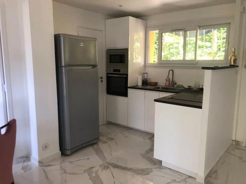 une cuisine avec un réfrigérateur en acier inoxydable et des armoires blanches dans l'établissement Design appartement, à Nice