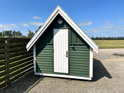 a green and white shed with a white door at Gård hytter in Tønder